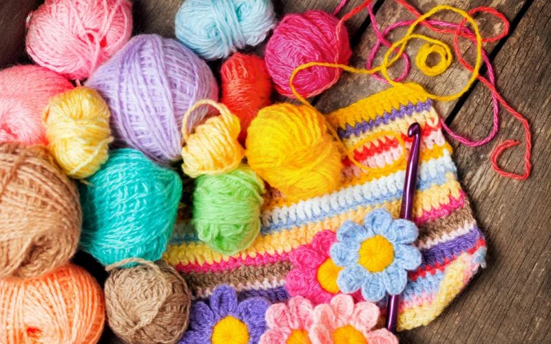 colorful yarn balls and crocheted fabric and flowers