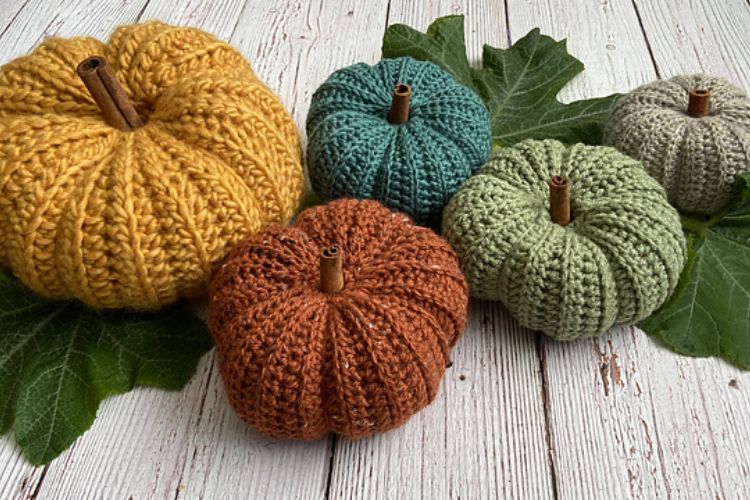 Four knitted pumpkins on a wooden table.