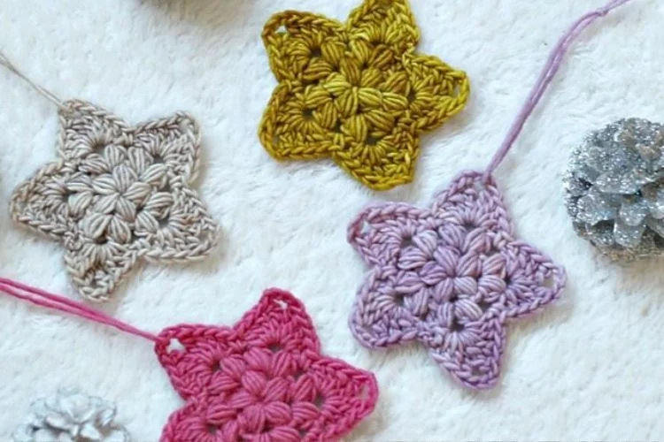 A group of crocheted star ornaments on a white blanket.