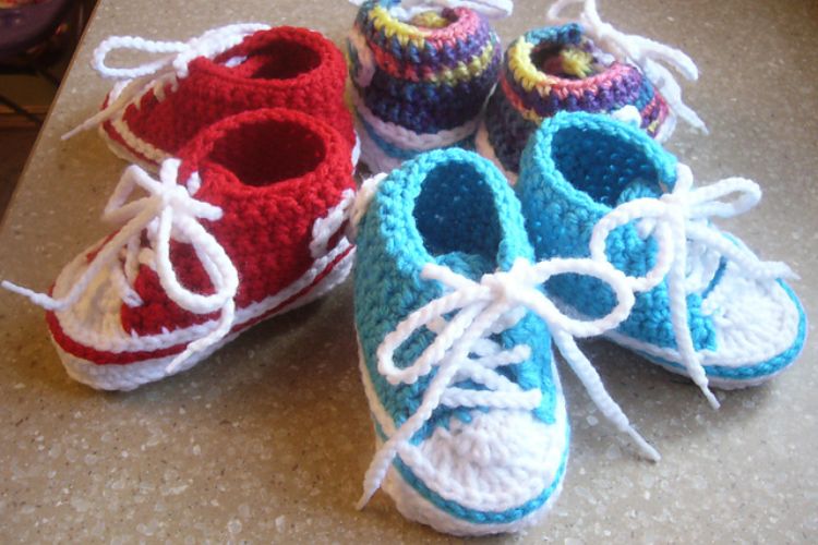 Four pairs of crocheted converse shoes on a counter.