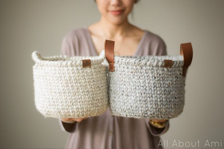 A woman showcasing two beautifully crocheted baskets.