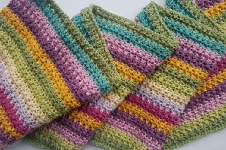 Three colorful crocheted dishcloths on a white surface.