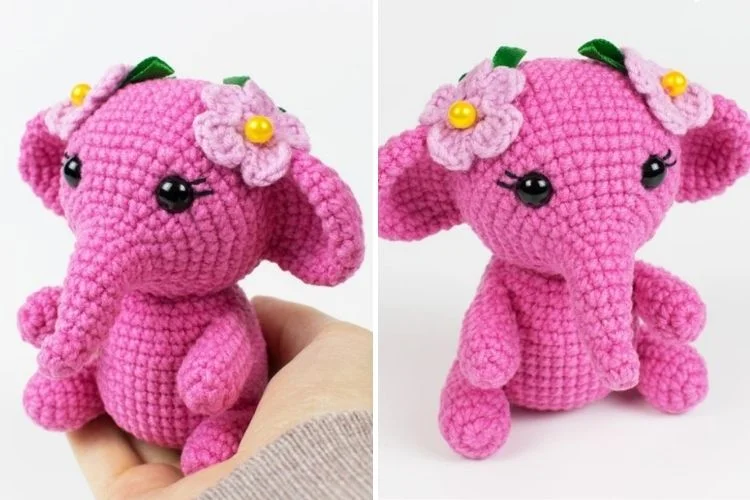 A pink crocheted elephant with flowers on its head.