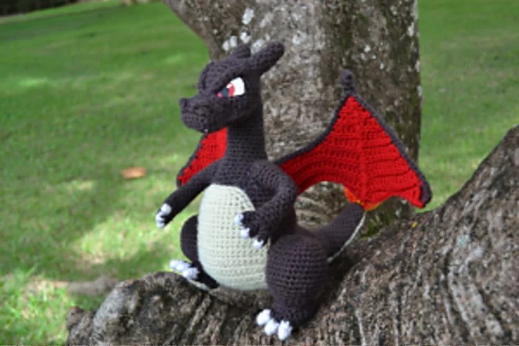 A crocheted toy pokemon sitting on a tree branch.