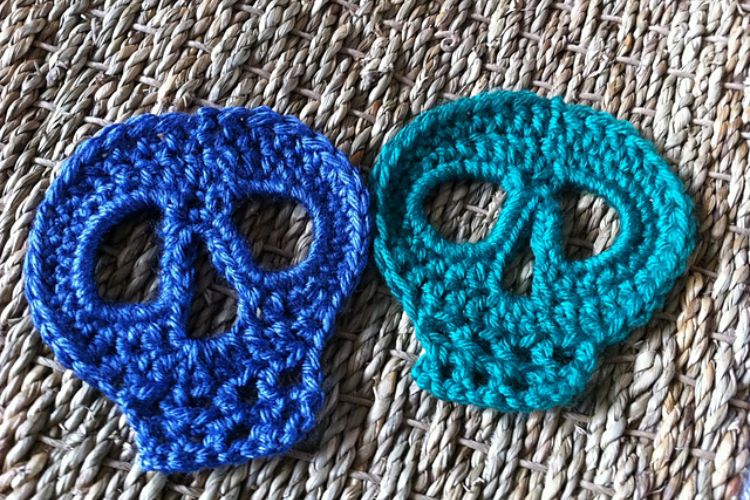 Two crocheted skulls on a rug.