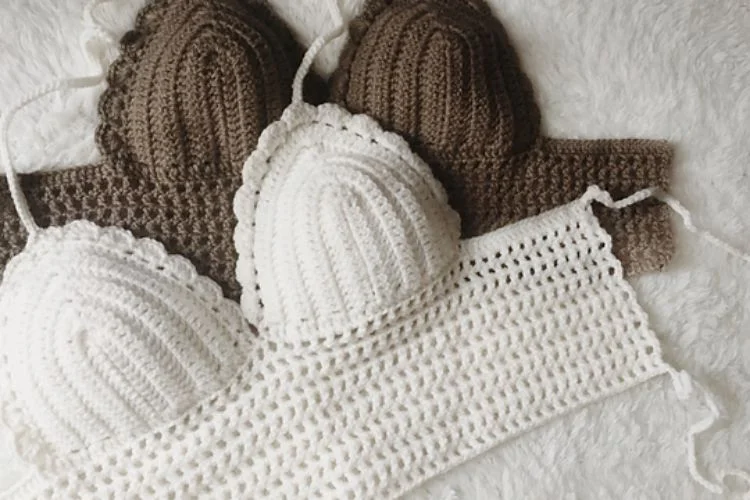 Two crocheted bikinis on a white blanket.