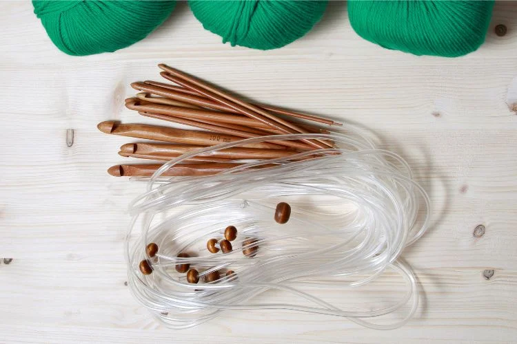 Knitting needles and yarn used to crochet a circle on a wooden table.