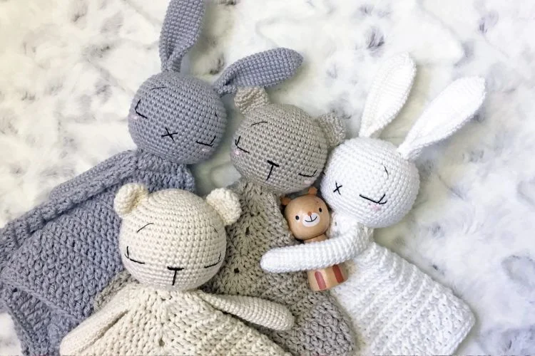 Three crocheted stuffed animals laying on top of each other.