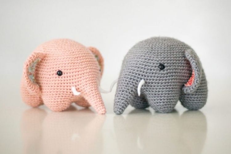 Two crocheted elephants sitting next to each other.