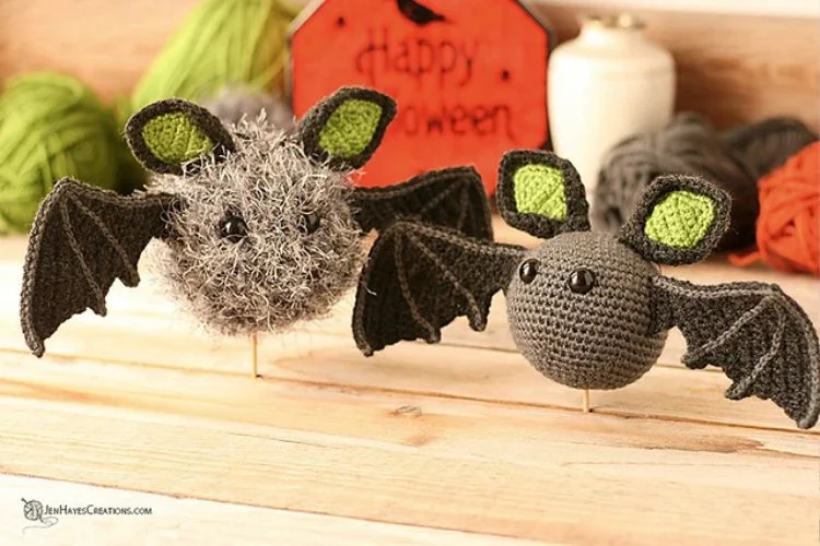 Two crocheted bats on a wooden table.