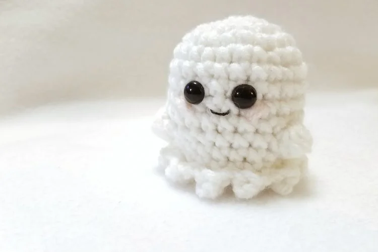 a small crochet ghost amigurumi in a white color