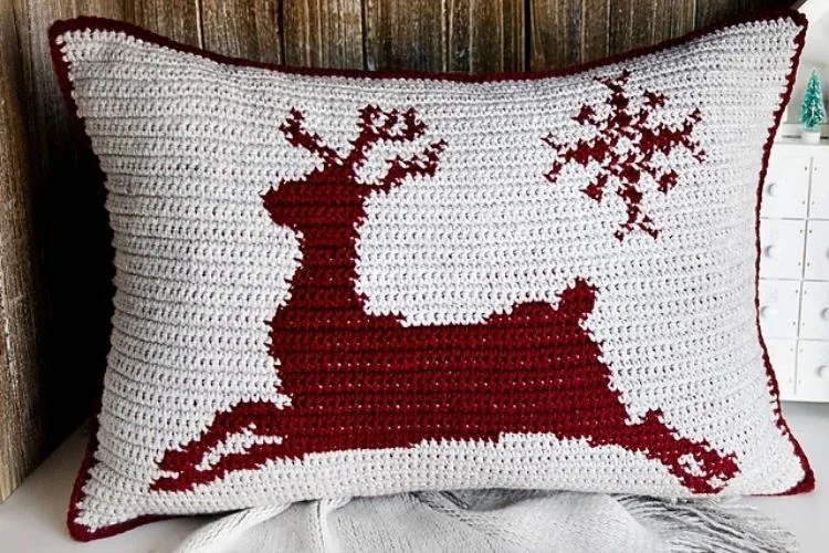 A crocheted pillow with a reindeer on it.