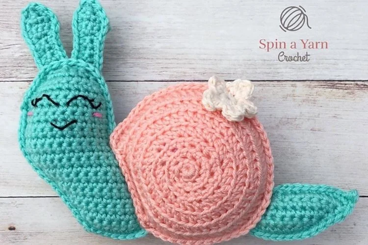 A crocheted snail on a wooden surface.