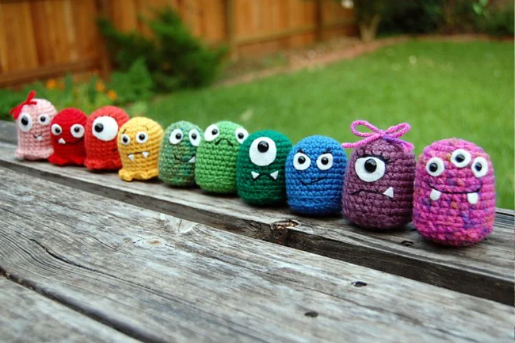 A group of crocheted monsters sitting on a wooden table.