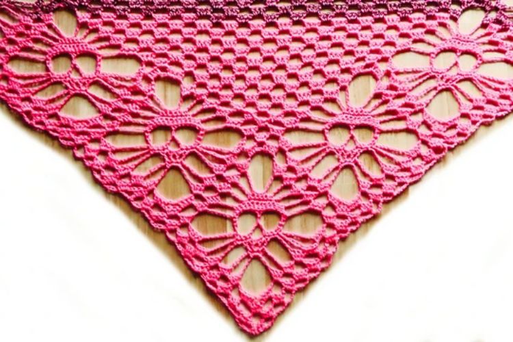 A pink crocheted skull shawl on a white surface.