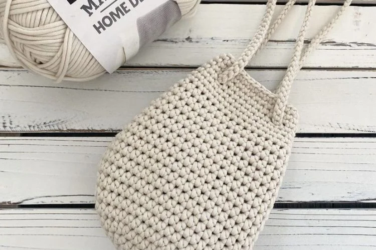 A crocheted bag with a ball of yarn next to it.