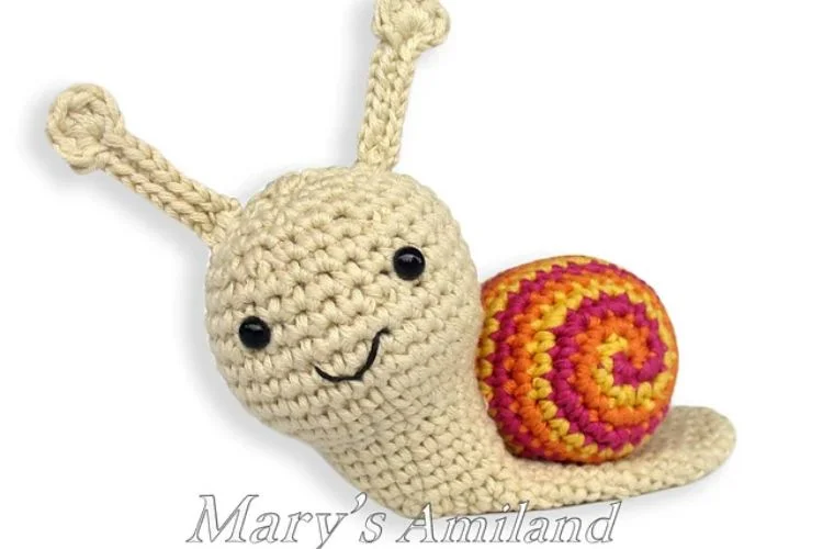 Amber Snail, the ami, is a crocheted snail with a colorful tail.