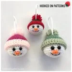 Three crocheted Snowman Baubles with hats in pink, red, and green, each with a white ribbon loop for hanging, displayed on a white background.