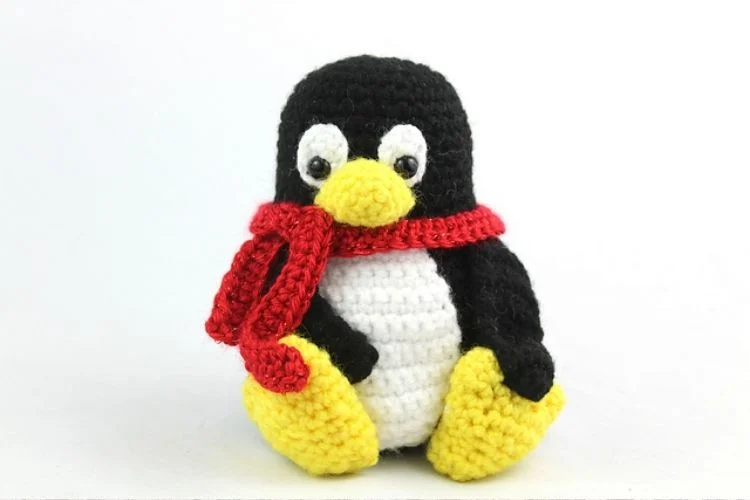 a crochet penguin amigurumi with a red scarf