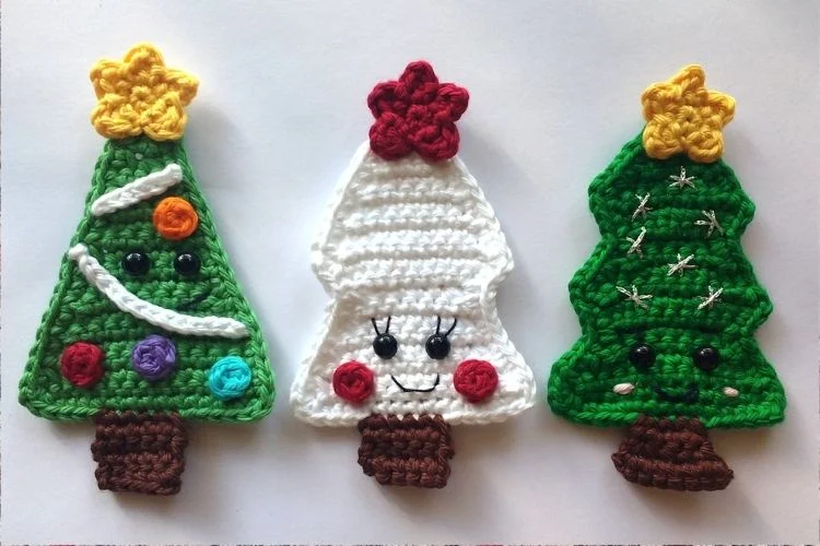 Three crocheted christmas trees on a white surface.