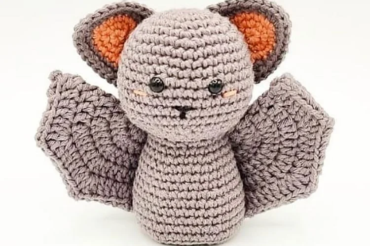 A crocheted bat amigurumi on a white background.