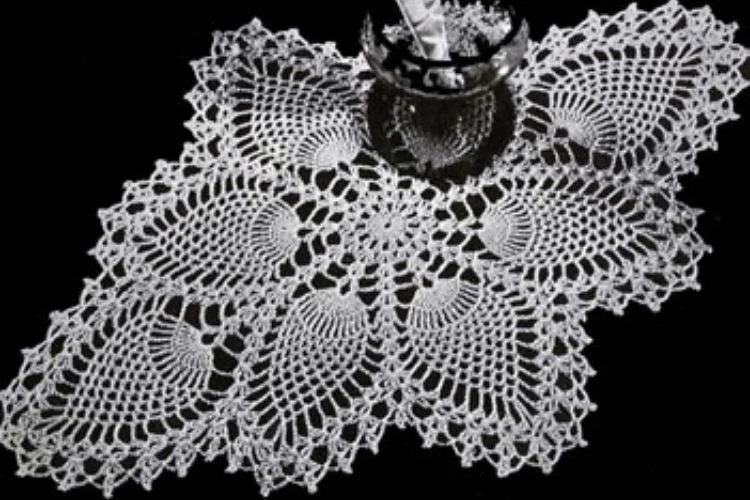 A white doily with a glass on it.