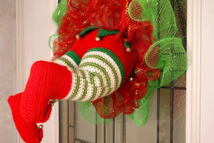 A crocheted elf wreath hanging on a door.