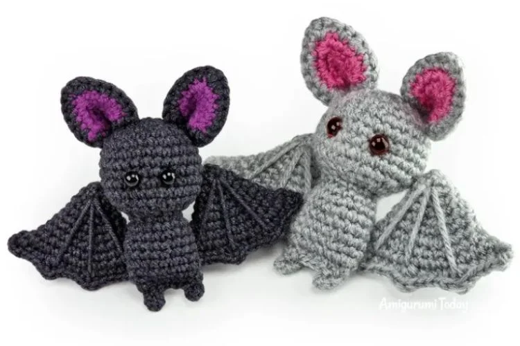 Two crocheted bats on a white surface.