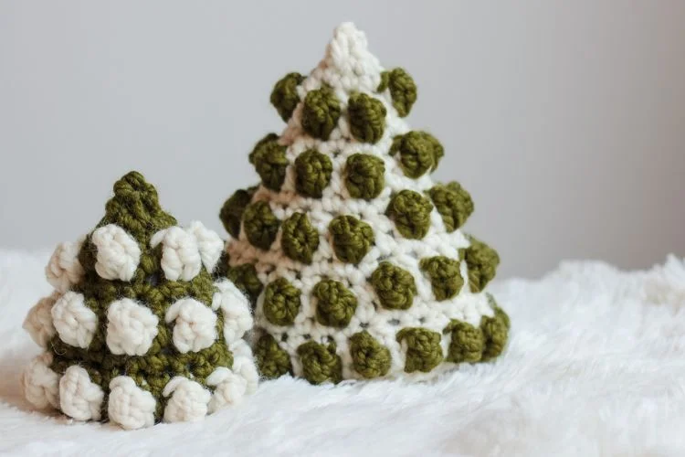 Two crocheted christmas trees on a white surface.