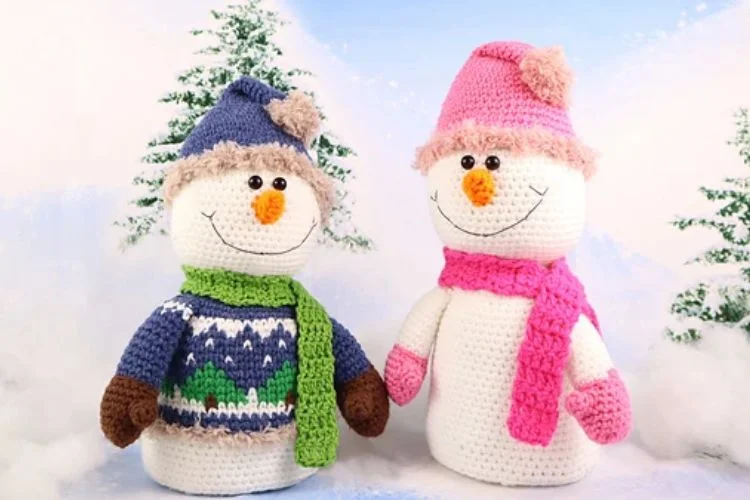 Two crocheted snowmen standing next to each other.