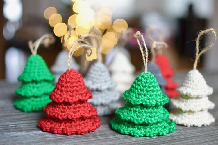 Crocheted christmas tree ornaments on a wooden table.