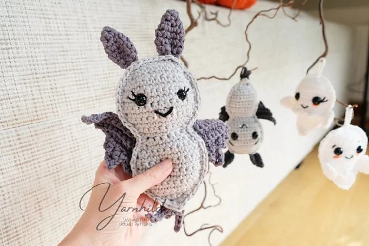 A person is holding a crocheted bat amigurumi.