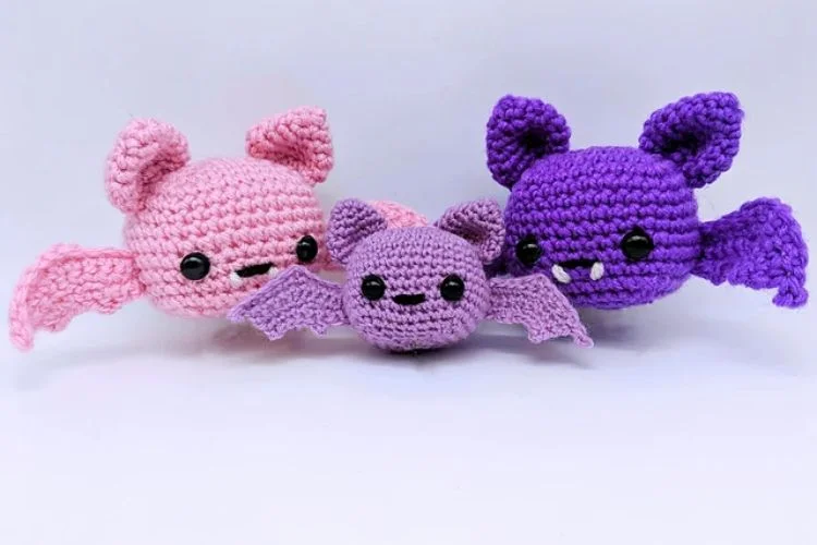 Three crocheted bats on a white surface.