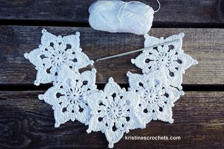 White crocheted snowflakes on a wooden table.