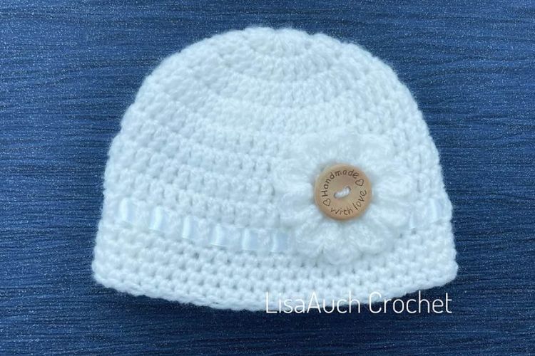 A white crocheted hat with a wooden button.