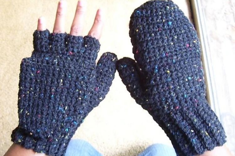 A person wearing black crocheted mittens.