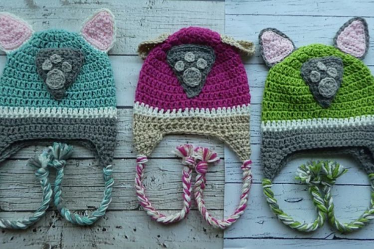 Three crocheted hats with paws on them.