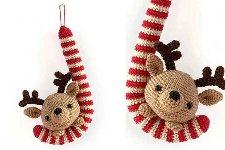 A crocheted reindeer hanging from a striped spool.