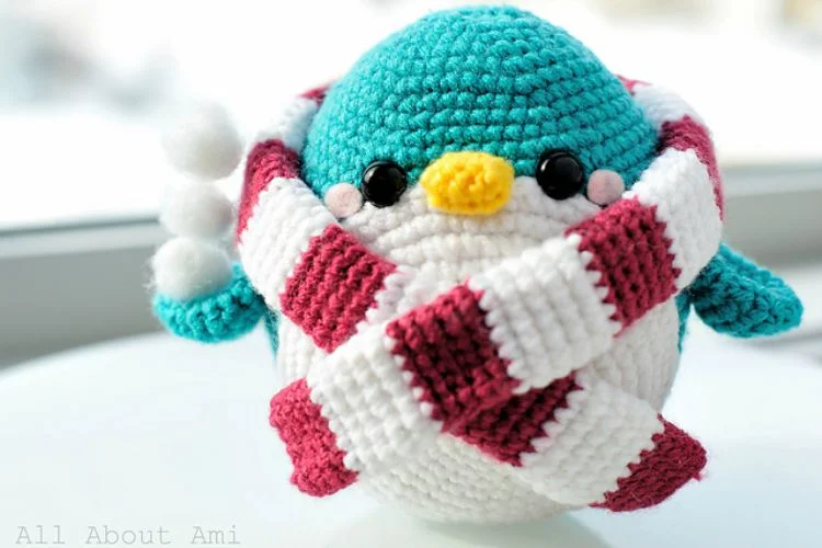 A crocheted penguin wearing a scarf.