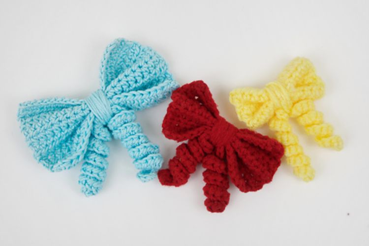 Three crocheted bows on a white surface.