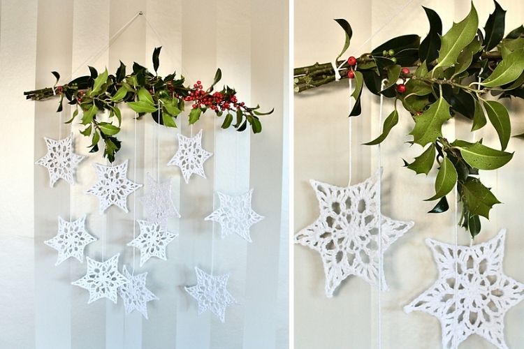 Snowflakes hanging from a branch with holly leaves.