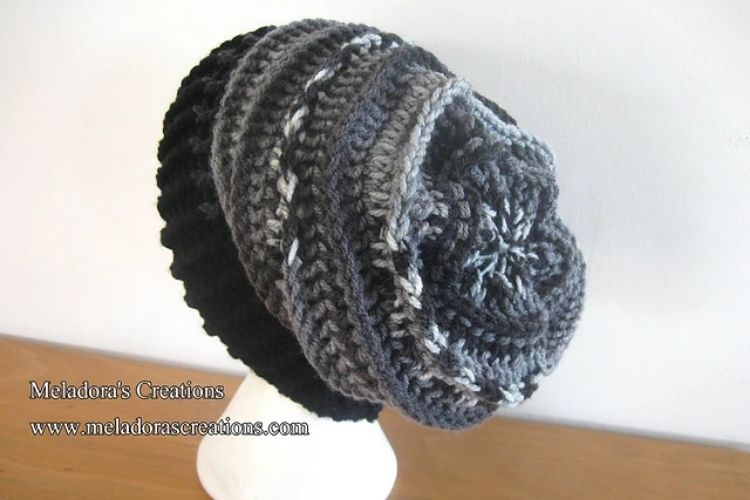 A black and grey crocheted hat on a mannequin.