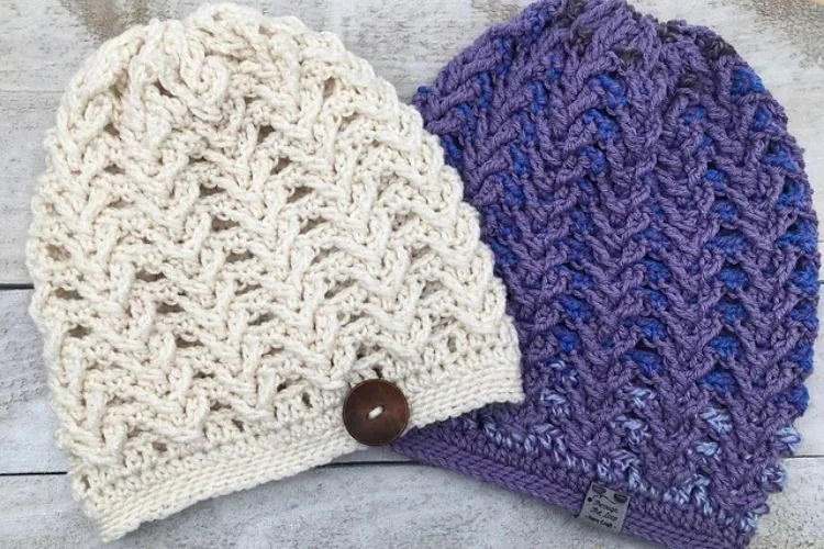 Two knitted beanie hats on a wooden surface.