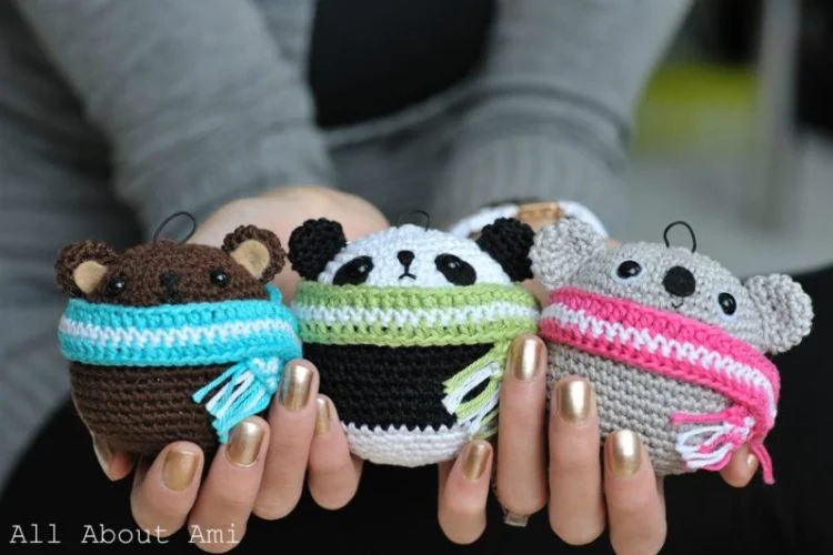 Three crocheted koala bears are held up by a person.