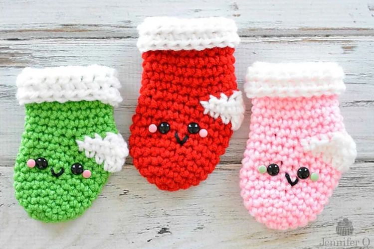 Three crocheted christmas stockings on a wooden surface.