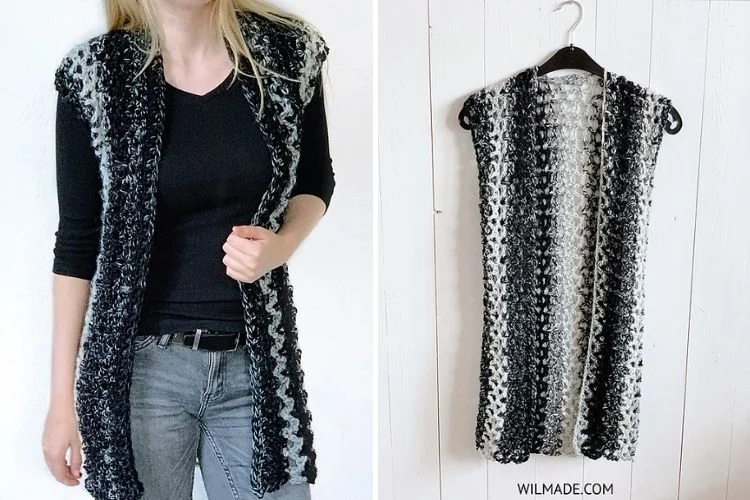 A black and white crocheted vest hanging on a hanger.