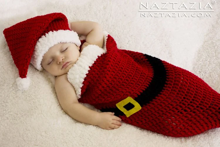 A baby sleeping in a crocheted santa claus.