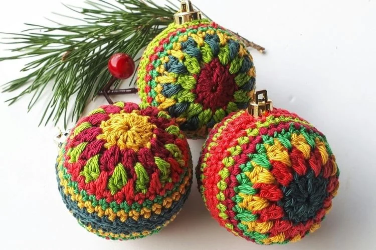 Three crocheted christmas ornaments on a white surface.