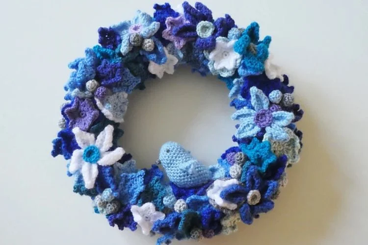 A blue and white crocheted wreath on a wall.