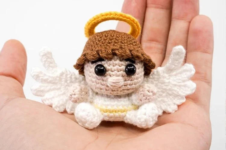 A small crocheted angel in a person's hand.